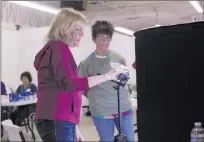  ?? Rachel Aston ?? Bev Balke, left, and Webe Webowitz set up a camera to photograph a Route 91 Harvest festival artifact at the Clark
County Museum in Henderson. Groups of volunteers are creating a permanent museum collection.
Las Vegas Review-journal