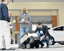  ?? Picture: AFP ?? DELIVERY SYSTEM: Starship Technologi­es executive Henry Harris-Burland, right, explains at the Washington Auto Show how the six-wheeled robots work