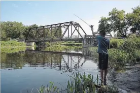  ??  ?? Miguel Capanas casts his fishing rod near the historic Black Bridge over the Speed River in Hespeler.