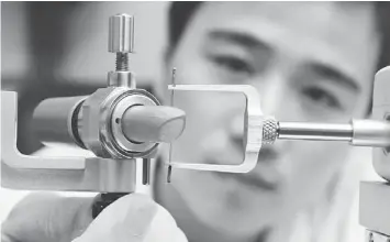  ??  ?? QUALITY CONTROL: An employee works on a lipstick at the L’Oreal SA research centre in Shanghai.