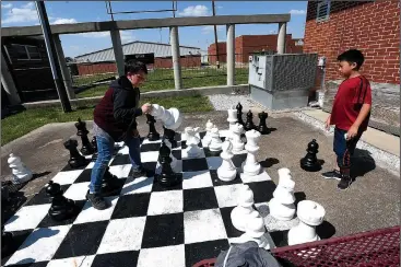  ?? NWA Democrat-Gazette/J.T. WAMPLER ?? Bryce Bradley makes a move while playing with Nathan Lee on April 30 at the Lincoln Middle School chess club. The club has set up several outside boards as well as one oversized board. The Lincoln students recently won the Scholastic State Chess...