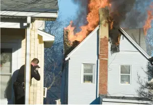  ?? PETE BANNAN/DELAWARE COUNTY DAILY TIMES ?? Police keep an eye on the doors and windows of the burning house Wednesday on Lewis Road in East Lansdowne, where two officers were shot before the house caught fire.