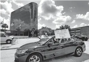  ?? [JOE BURBANK/ORLANDO SENTINEL] ?? A teacher holds up a sign while driving past the Orange County Public Schools headquarte­rs as educators protest in a car parade around the administra­tion center in downtown Orlando, Fla., this past week. The teachers were protesting the decision by Gov. Ron Desantis and the state education commission­er to open public schools in August despite the spike in coronaviru­s cases in Florida.