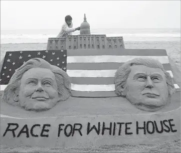  ?? European Pressphoto Agency ?? ARTIST SUDARSHAN PATTNAIK puts some finishing touches on a sand sculpture featuring U.S. presidenti­al candidates Hillary Clinton and Donald Trump at Puri Beach in the state of Orrisa, India.