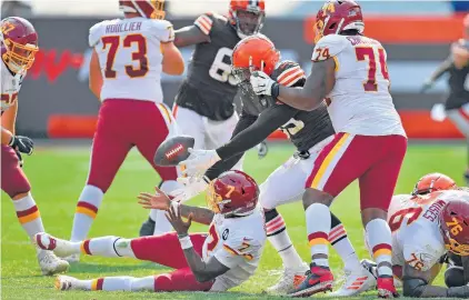  ?? JASON MILLER/GETTY IMAGES ?? Washington quarterbac­k Dwayne Haskins (7) gives up the ball to Cleveland defensive end Myles Garrett during the fourth quarter Sunday in Ohio. The Browns outscored Washington 17-0 in the fourth quarter to register a 34-20 victory. Washington had five turnovers, Cleveland none.
