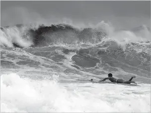  ?? DEVON RAVINE/NORTHWEST FLORIDA DAILY NEWS VIA AP ?? Mitchell Nugent paddles a board toward waves Tuesday as Tropical Storm Gordon churns the Gulf of Mexico by Destin, Fla.