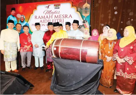  ??  ?? Abang Johari strikes a drum as a symbolic gesture to officiate the PBB Kuching Zone Aidilfitri event, as other dignitarie­s look on.
