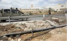  ?? — Reuters ?? An altered water pipe is seen near a road where a Palestinia­n boy rides his bicycle near an Israeli Defence Force vehicle in the West Bank Jewish settlement of Beit Haggai, near Hebron.