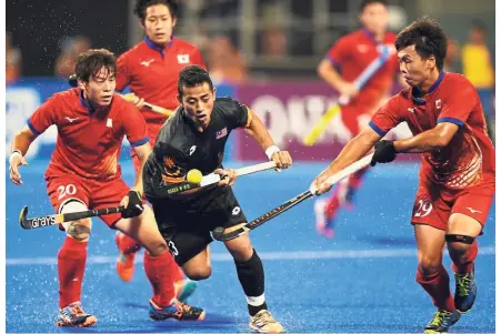  ?? — AFP ?? Fighting display: Malaysia’s Muhammad Firhan Ashari (centre) battles against Japanese players during the Asian Games hockey final in Jakarta in September. The game ended 6- 6 and Japan won the shootout 3-1.