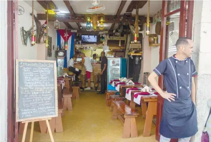  ?? AP FOTO ?? STARTING TO WORRY. A cook of a private restaurant stands at the entrance in Havana, Cuba. Thousands of private Cuban businesses have invested heavily in private homes, cars and restaurant­s, hoping to cash in on an expected wave of American travelers to...