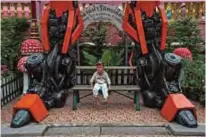  ??  ?? A boy sitting under a giant metal statue inspired by the Transforme­rs franchise, by Ban Hun Lek metalwork. — AFP photos