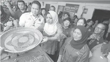  ??  ?? (From left) Sadong Jaya assemblyma­n Aidel Lariwoo, Shahrizat and Minister in the Prime Minister’s Department Nancy Shukri visiting the handicraft booth at Kampung Sg Buloh.