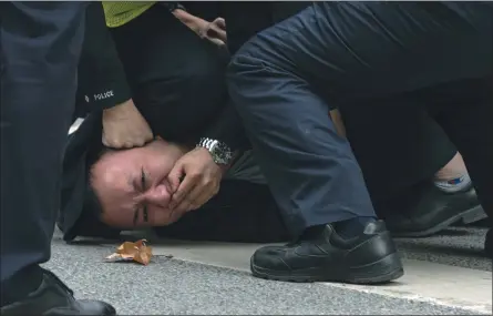  ?? THE ASSOCIATED PRESS ?? Chinese police officers pin down a protester and cover his mouth during a protest on a street in Shanghai on Nov. 27. Protesters have expressed anger over China’s harsh COVID-19policies that they believed played a role in the deadly fire Nov. 24in a city in the far west.