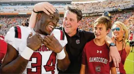  ?? MICHAEL REAVES / GETTY IMAGES ?? South Carolina coach Will Muschamp (center) celebrates with his son, Whit Muschamp (right), and Mon Denson after beating Tennessee 15-9.