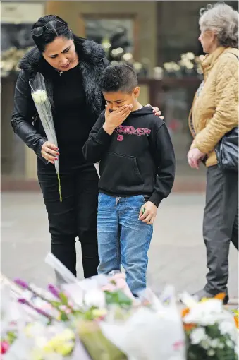  ?? JEFF J. MITCHELL/GETTY IMAGES ?? People pause to look at tributes in St. Ann’s Square in Manchester, England, to victims of the explosion at Manchester Arena on Monday. Rather than giving in to the fear inspired by terrorism, parents need to help their kids triumph over the darkness,...
