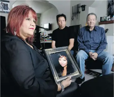  ?? LYLE STAFFORD /Postmedia News ?? Brenda Dyck, the sister in-law of Kim Smith holds her portrait as her father, Gord Smith, right, and brother Trevor Smith, centre, look on in her Winnipeg, Manitoba home. Kim Smith, went to hospital last year for an elective hysterecto­my. She
died...
