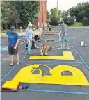  ??  ?? Members of College Hill Presbyteri­an Church join other volunteers painting a Black Lives Matter mural in the parking lot of the Tulsa church. [PHOTO PROVIDED]