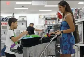  ?? THE ASSOCIATED PRESS ?? Luke Vega, 7, left, looks in a cart with his mother Kimberly Vega, right, as they shop at a Kohl’s store in Concord, N.C.