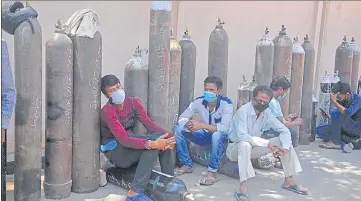  ??  ?? Kin of Covid patient wait for their turn to refill oxygen cylinders outside a refilling centre in Lucknow on Monday.