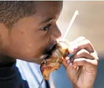  ??  ?? Ziandrew Pina, 6, of Dorchester munched on a pork kebab, called a pincho in Cape Verde, at Ceylon Park.