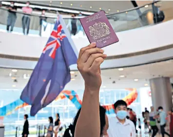  ??  ?? A Hong Kong protester holds a British National Overseas passport and colonial flag at a demonstrat­ion against Chinese interferen­ce