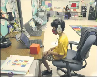  ?? EMILY MICHOT - THE ASSOCIATED PRESS FILE PHOTO ?? Nova Blanche Forman Elementary School teacher Attiya Batool, teaches her 4th grade class virtually as her son, Nabeel, does his second grade classwork online wearing a face mask and headphones during the first day of school last month in Broward, in Davie, Fla. This year, many families are dealing with a first: building their back-to-school shopping plans around distance learning.