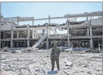  ?? Evgeniy Maloletka The Associated Press ?? A Ukrainian serviceman on Wednesday looks at university buildings that were destroyed by a Russian attack in Kharkiv, eastern Ukraine.