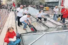  ?? FOTOS (3): UWE MISERIUS ?? Karnevalis­ten im Einsatz für eine saubere Stadt: Die Roten Funken putzten eifrig das Glasdach am Funkenplat­z.