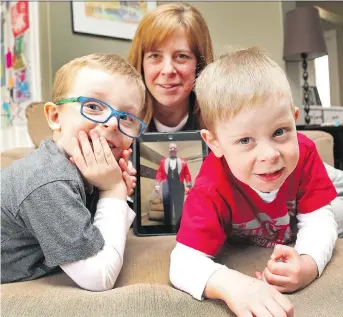  ?? JEAN LEVAC ?? Nicole Code with a picture of her husband, and their sons Brock, left, and Duncan. Code’s husband, Jeff, is overseas with the Canadian Armed Forces and she’s upset at the cost of shipping packages to him.