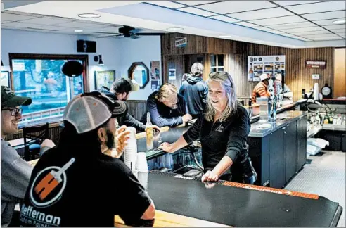  ?? ARMANDO L. SANCHEZ/CHICAGO TRIBUNE ?? Owner Joan Ward talks with patrons while working behind the bar at Papa’s Blue Spruce Resort on May 14 in Lake Geneva, Wisconsin.