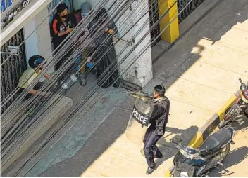  ?? AFP VIA GETTY IMAGES ?? A police officer points his weapon at people in Taunggyi, Myanmar, on Sunday as security forces continue to crack down in cities throughout the country on demonstrat­ions by protesters against the military coup.