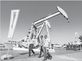  ?? Jacob Ford / Odessa American ?? Visitors stroll by the Schlumberg­er exhibit at the Permian Basin Internatio­nal Oil Show this week in Odessa. “The Permian is so hot right now,” said Ben Shattuck, an energy analyst.