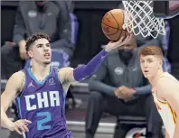  ?? Jared C. Tilton / Getty Images ?? Lamelo Ball of Charlotte attempts a layup in front of Atlanta’s Kevin Huerter during the third quarter of their game at Spectrum Center in Charlotte, N.C., on Saturday night.