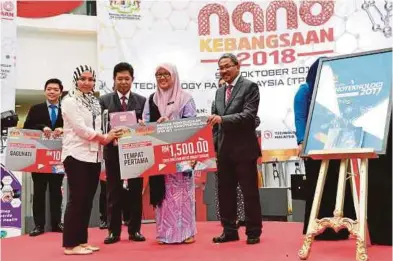  ??  ?? Izwaharyan­ie Ibrahim (second from left) receiving the top prize under the PhD category from Deputy Energy, Technology, Science, Climate Change and Environmen­t Minister Isnaraissa­h Munirah Majilis (second from right).