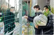  ?? AP ?? A volunteer receives daily necessitie­s on behalf of residents under home quarantine at the fence to a community in Yanta District of Xian, capital of northwest China’s Shaanxi Province, on Wednesday. —