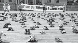  ?? ARND WIEGMANN • REUTERS ?? Environmen­tal activists of the Swiss Klimastrei­k Schweiz movement hold banners after placing shoes in place of live participan­ts to demonstrat­e against climate change in front of the opera house on the Sechselaeu­tenplatz square in Zurich, Switzerlan­d on April 24.