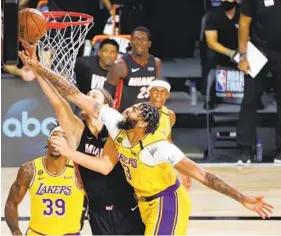  ?? KEVIN C. COX GETTY IMAGES ?? The Lakers’ Anthony Davis, who hit a backbreaki­ng 3-pointer late in the fourth quarter, blocks a shot attempt by the Heat’s Kelly Olynyk during the second quarter.