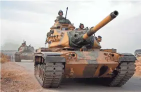  ?? AREF TAMMAWI/AFP VIA GETTY IMAGES ?? Turkish soldiers drive US-made tanks through Tukhar, Syria, on Monday as Turkey continues its assault.