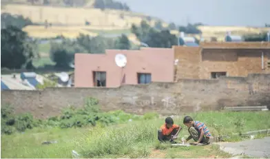  ??  ?? VULNERABLE. Two boys play in Riverlea. Tens of thousands of residents live at the foot of mine dumps, which are vestiges of gold mining which now threatens the health of township residents.