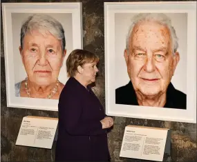  ?? AP PHOTO/MARTIN MEISSNER ?? German chancellor Angela Merkel stands in front of a portrait of Holocaust survivor Naftali Furst, right, during the opening Tuesday of the exhibition ‘Survivors - Faces of Life after the Holocaust’ at the former coal mine Zollverein in Essen, Germany.