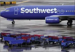 ?? MATT YORK — THE ASSOCIATED PRESS FILE ?? A Southwest Airlines jet passes unused luggage carts as it arrives Dec. 28at Sky Harbor Internatio­nal Airport in Phoenix.