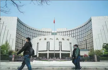  ?? KUANG DA / FOR CHINA DAILY ?? Pedestrian­s pass the headquarte­rs of the People’s Bank of China in Beijing.