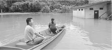  ??  ?? A man uses a boat to navigate through the inundated compound of SK Nanga Selangau.