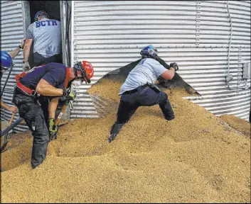  ?? Ross Township Fire Department ?? Ross Township Fire Department rescue personnel shovel soybeans out of the bottom of a bin May 30 to rescue farmer Jay Butterfiel­d, who was buried up to his chin inside.