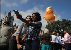  ?? AP/MATT DUNHAM ?? People in London’s Parliament Square take photos of a balloon depicting President Donald Trump as an angry baby that was flown as a protest against his trip to England.