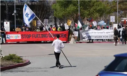  ?? Photograph: Nathan Frandino/Reuters ?? A counter-protester holding an Israeli flag walks into the parking lot near a protest at Google Cloud offices in Sunnyvale, California, on Tuesday.