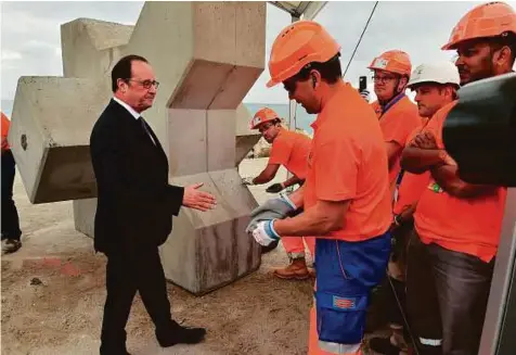  ?? AFP ?? French President Francois Hollande (left) shakes hands with workers during a ceremony to mark the laying of the first stone of the extension of the port of Calais in northern France yesterday.