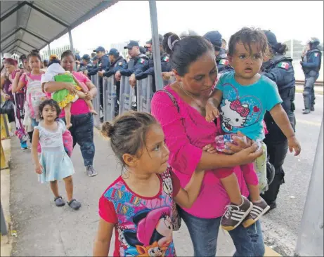  ??  ?? Algunas familias hondureñas cruzan el puente fronterizo del río Suchiate, luego que las autoridade­s mexicanas autorizara­n su paso para luego ser llevadas a albergues