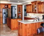  ??  ?? The tiled kitchen is   tted with wood cabinetry, a granite-topped island and stainless-steel appliances.