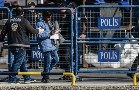  ?? OZAN KOSE/AFP/GETTY IMAGES ?? A Turkish police officer escorts one of 200 migrants who were deported from Greece on Monday. The deportatio­n has alarmed human rights groups.